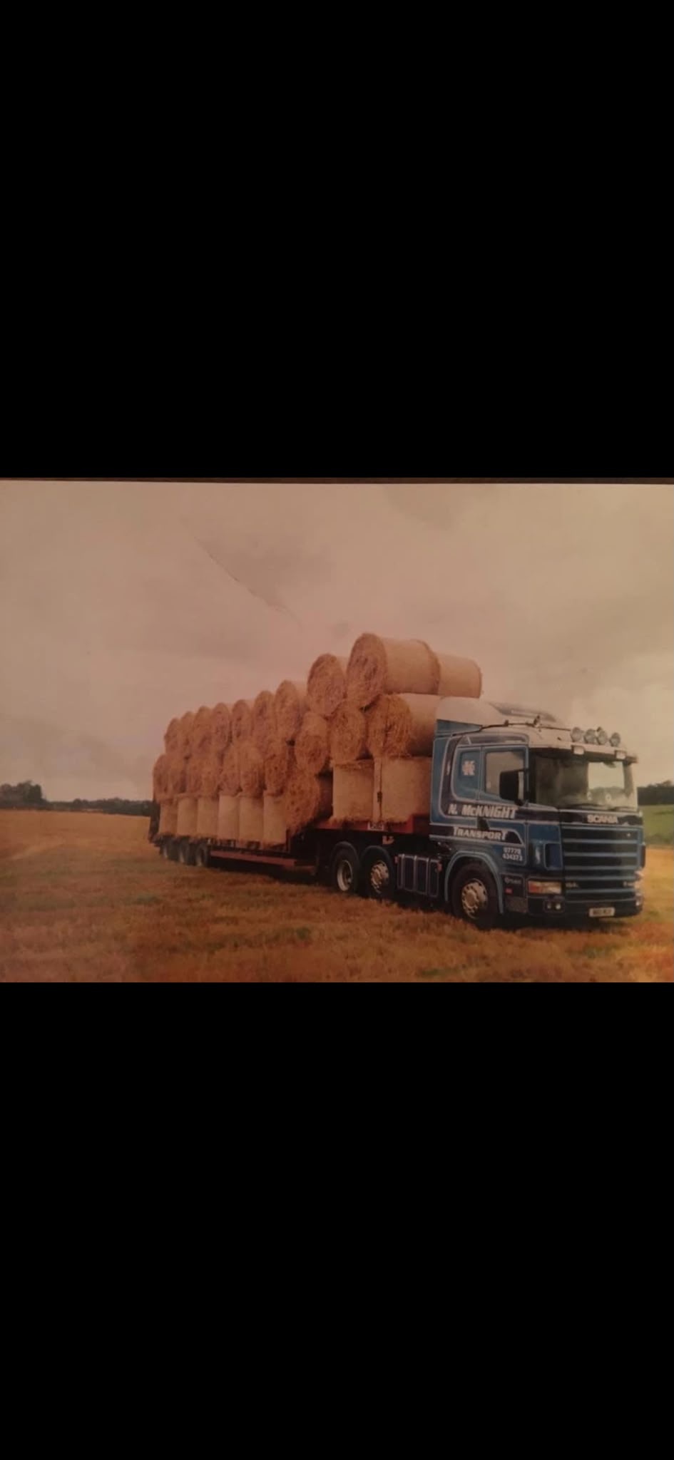 Historic McKnight truck carrying bales in a field