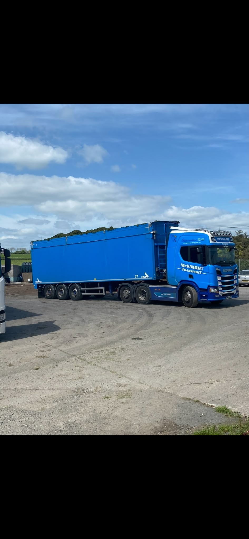Side view of a blue McKnight Scania and high-sided bulk trailer