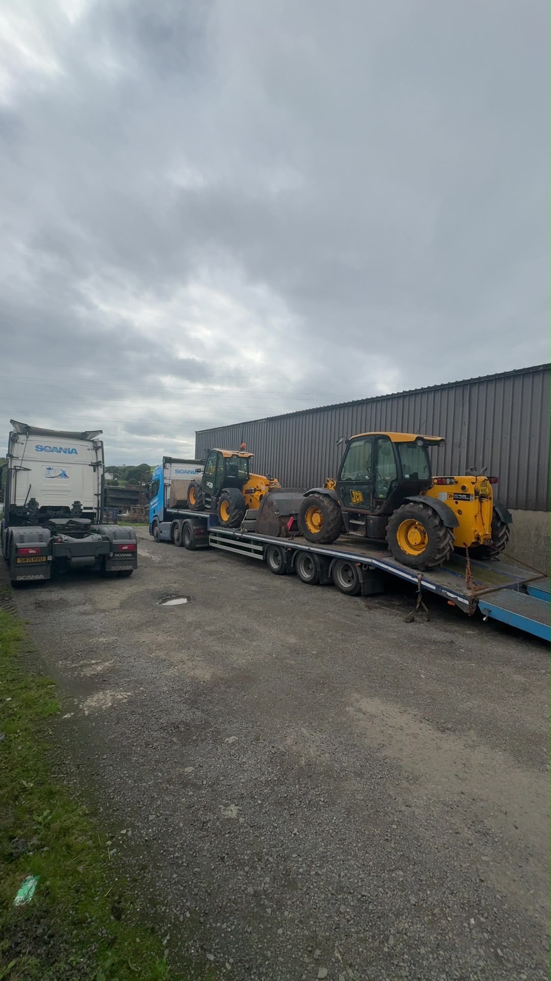 Two JCB machines carried on a low-loader trailer behind a blue McKnight lorry