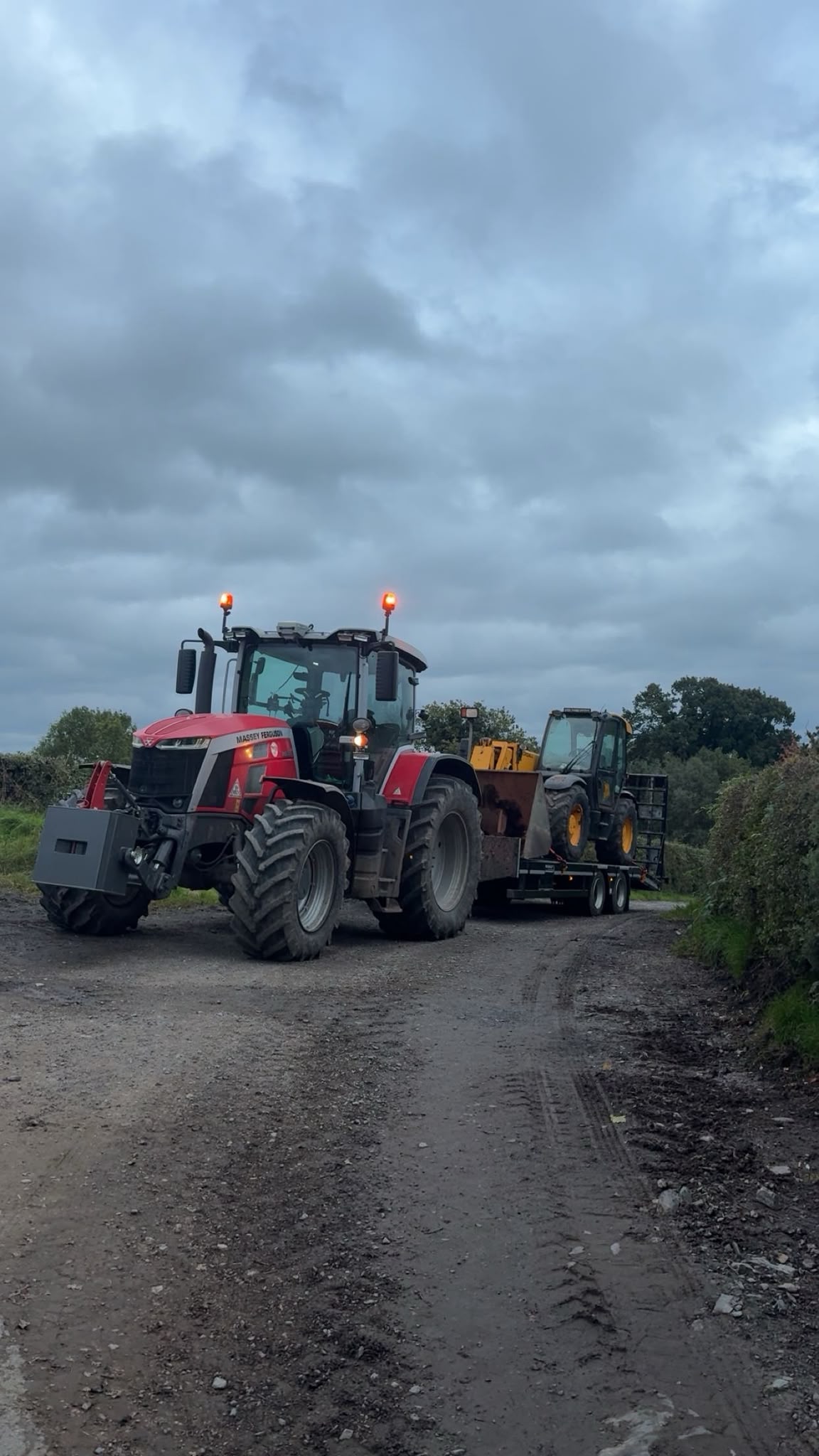 Massey Ferguson tractor towing a trailer carrying JCB loading equipment